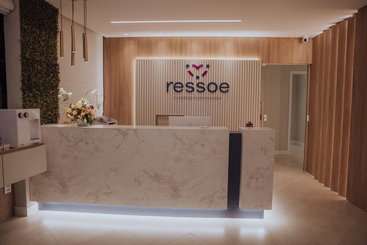 Recepção da Clínica Ressoe com balcão de mármore e logo iluminado